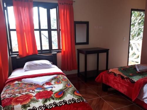 a bedroom with a bed and a window with red curtains at Hospedaje y Camping Buena Vista in San Agustín