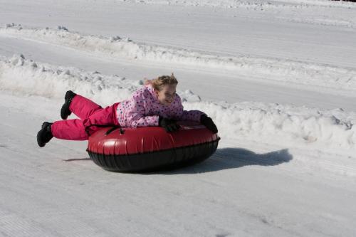 a young girl is riding on a sled in the snow at Rimfire in Snowshoe