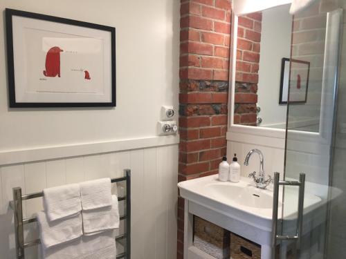 a bathroom with a white sink and a brick wall at The Studio at Northfield in Methven
