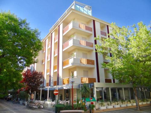 a tall white building with balconies on a street at Hotel Aquila D'Oro in Misano Adriatico