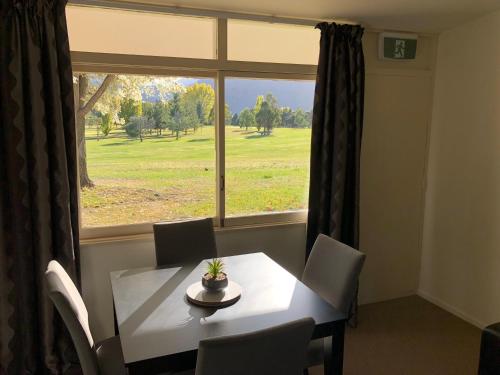 ein Esszimmer mit einem Tisch und einem Fenster in der Unterkunft Waitaki Lakes Apartments - Otematata in Otematata