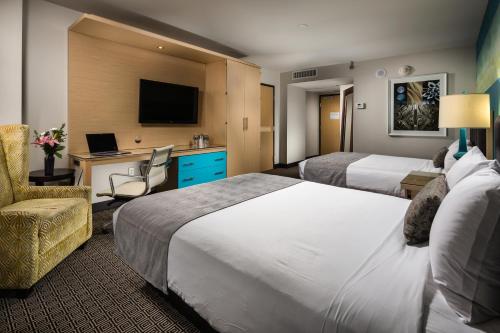 a hotel room with two beds and a desk with a laptop at Downtown Grand Hotel & Casino in Las Vegas