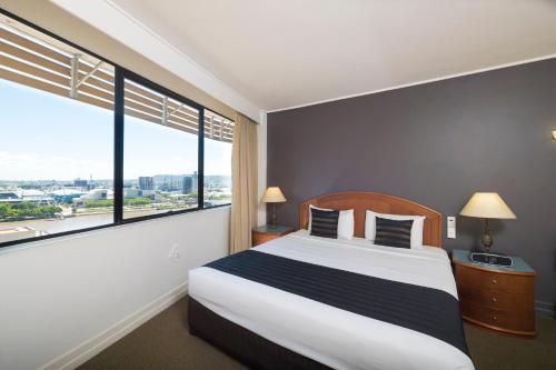 a bedroom with a large bed with a large window at Great Southern Hotel Brisbane in Brisbane