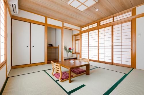 a room with a wooden table and chairs and windows at PLUS 9 Station INN in Izumi-Sano