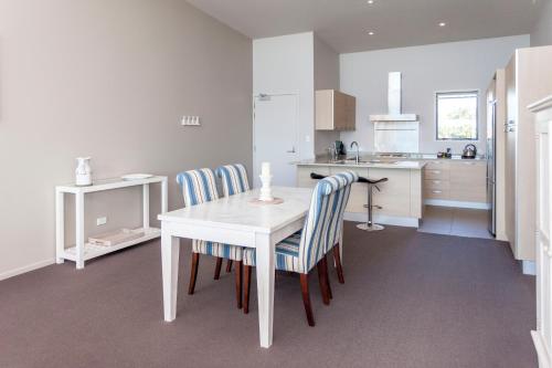 a kitchen with a white table and chairs at Sovereign Pier On The Waterways in Whitianga