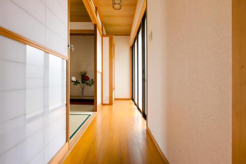 an empty hallway with wood floors and large windows at PLUS 9 Station INN in Izumi-Sano