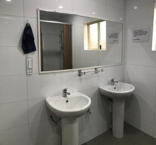 a white bathroom with two sinks and a mirror at Hay Street Traveller's Inn in Perth