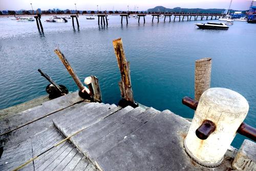 a wooden dock in the water with a boat at Phuket Paradiso in Chalong 