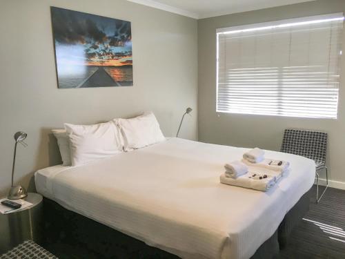 a bedroom with a large white bed with towels on it at The Premier Hotel Broadmeadow in Newcastle