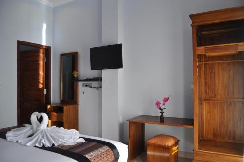 a bedroom with a bed and a tv on the wall at Pradana Beach Inn Luxury in Nusa Penida