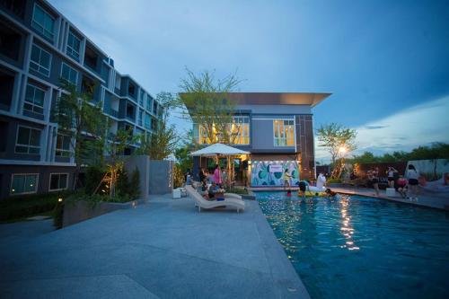 a hotel with a swimming pool in front of a building at Diamant Modern Room Condominium Resort in Chiang Mai