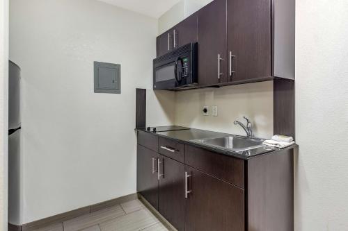 a kitchen with wooden cabinets and a sink at Studio 6-Orange, TX in Orange
