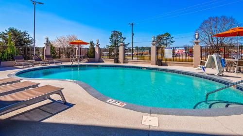 a swimming pool with chairs and an umbrella at Best Western Travelers Rest/Greenville in Travelers Rest