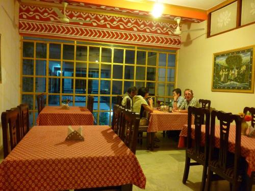 a group of people sitting at tables in a restaurant at Hotel Harmony in Khajurāho