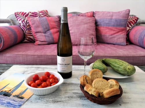a bottle of wine and a bowl of bread and a glass at Aqua & Terra Traditional Cave Houses in Oia