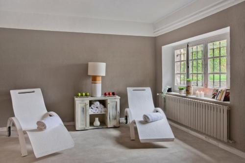 a living room with two white chairs and a window at Hotel Luze El Toro in Berrioplano