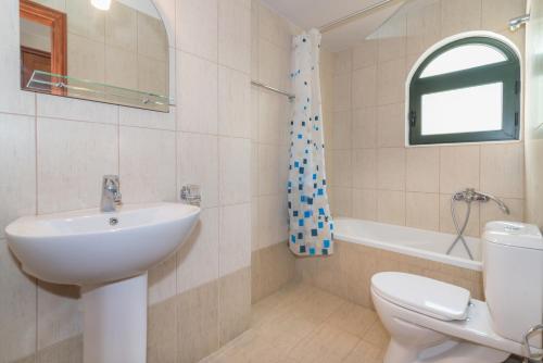 La salle de bains est pourvue d'un lavabo, de toilettes et d'une baignoire. dans l'établissement Allegro Studios & Apartments, à Marathias