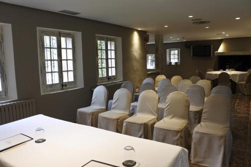 a room with white chairs and tables and windows at Hotel Luze El Toro in Berrioplano