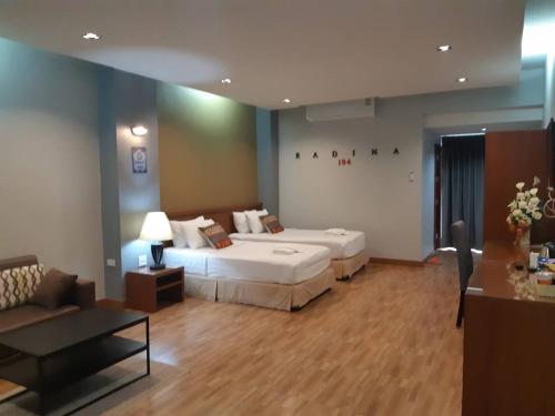 ナコーンシータンマラートにあるRadina Residenceのベッド2台とソファが備わるホテルルームです。