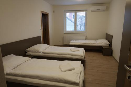 three beds in a room with a window at Apartmán Matyáš in Drnholec