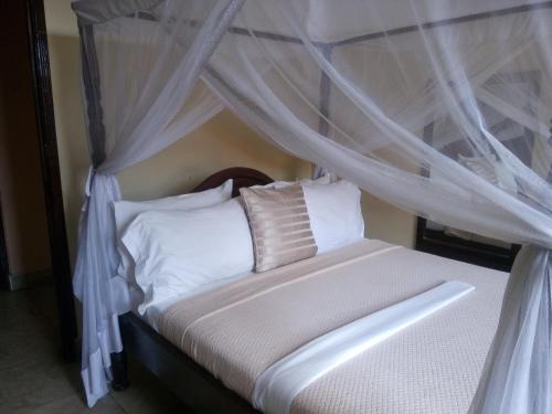 a bedroom with a canopy bed with white sheets and pillows at Transit Motel Ukonga in Dar es Salaam