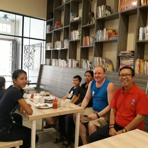 a group of people sitting around a table in a library at Arya Inn in Pematangsiantar