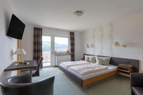 um quarto de hotel com uma cama, uma secretária e uma televisão em Luckai Hotel & Restaurant Inhaber Dennis Burmann em Freienohl