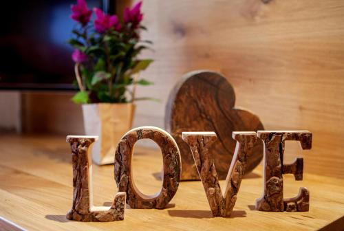 a wooden sign that says love on a table with flowers at Hotel Natur-Landhaus Krone in Maierhöfen