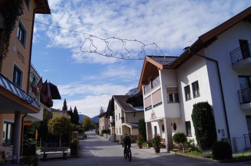 a person riding a bike down a street with buildings at Hotel Gänsleit in Söll