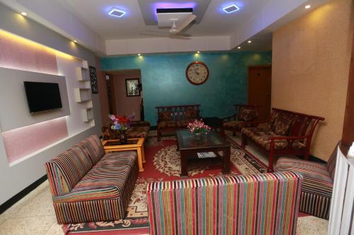 a living room with couches and a clock on the wall at Nagar Valley Hotel Ltd. in Dhaka