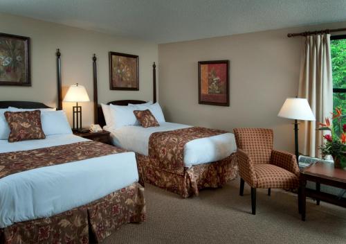 a hotel room with two beds and a desk and a chair at Maritime Inn Antigonish in Antigonish