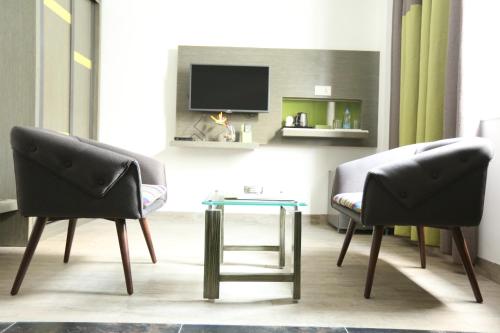 two chairs and a table in a room with a tv at Hotel Jump In & Out in Coimbatore