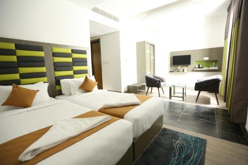 a hotel room with two beds and a living room at Hotel Jump In & Out in Coimbatore