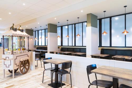 a restaurant with tables and chairs and windows at ibis Styles Nieuwpoort in Nieuwpoort