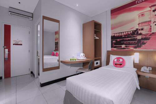 a bedroom with a white bed with a pink face pillow at favehotel Braga in Bandung