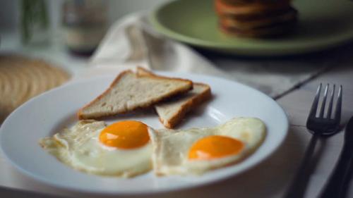 dos huevos y tostadas en un plato blanco con un tenedor en Hotel Sheela, 100m from Taj Mahal, en Agra