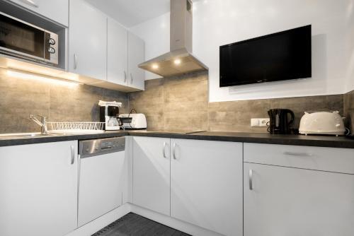 a kitchen with white cabinets and a flat screen tv at Landhaus Brigitte in Flachau