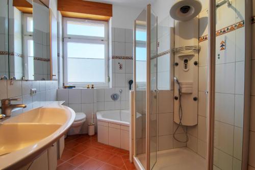 een badkamer met een bad, een wastafel en een douche bij Ferienwohnung Renchglück in Renchen