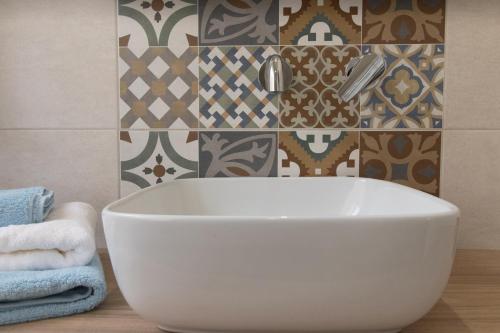 a white tub in a bathroom with a tile wall at Civico 1 in San Mauro Cilento