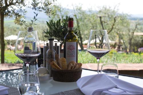 a table with two glasses of wine and a basket of bread at Locanda Le Piazze in Castellina in Chianti
