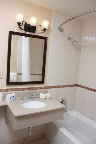 a bathroom with a sink and a tub and a mirror at Maritime Inn Antigonish in Antigonish