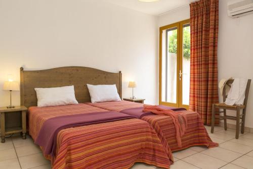 - une chambre avec un grand lit et une grande fenêtre dans l'établissement Résidence Odalys Les Hameaux de Capra Scorsa, à Belgodère