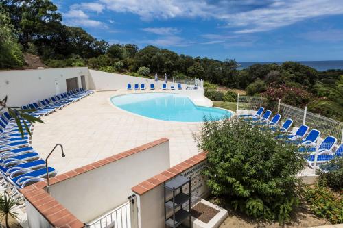 - une piscine entourée de chaises bleues dans l'établissement Résidence Odalys Les Hameaux de Capra Scorsa, à Belgodère