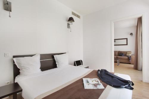 a bedroom with a large white bed and a couch at Appart'hôtel Odalys City - Monaco Les Hauts de la Principauté in Beausoleil