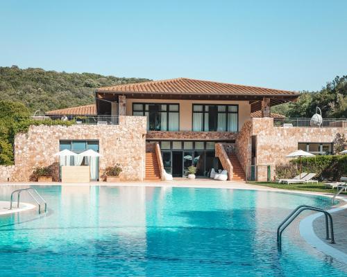 a villa with a swimming pool in front of a house at Argentario Lagoon Resort & Spa in Monte Argentario