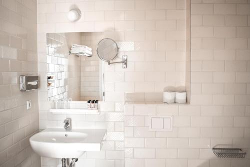 a white bathroom with a sink and a mirror at Hotel The Exchange in Amsterdam