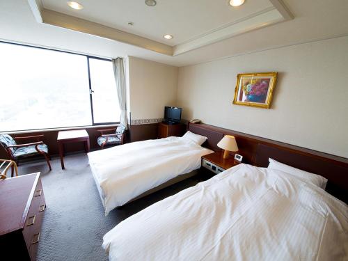 a hotel room with two beds and a window at Naruto Grand Hotel Kaigetsu in Naruto