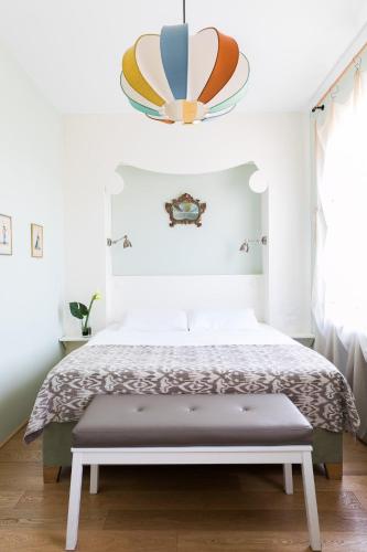 a white bedroom with a bed and a chandelier at Rarity Suites in Rome