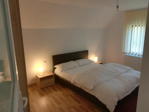 1 dormitorio con 1 cama blanca y 2 lámparas en Casa Fluțar, en Moisei