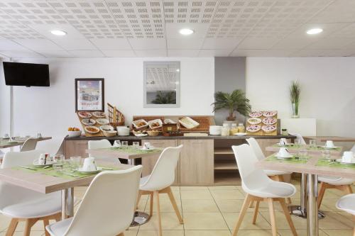 a dining room with tables and white chairs at Appart'hôtel Odalys City - Monaco Les Hauts de la Principauté in Beausoleil